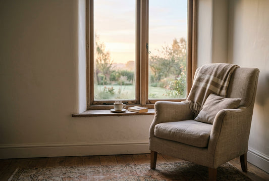 An empty armchair by a window at dawn.